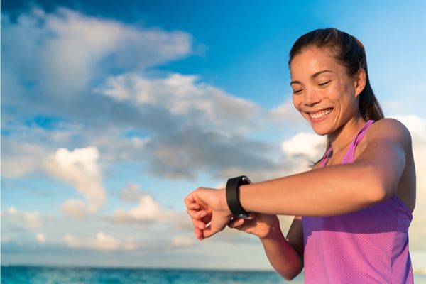 A happy female runner checks her GPS watch during a marathon